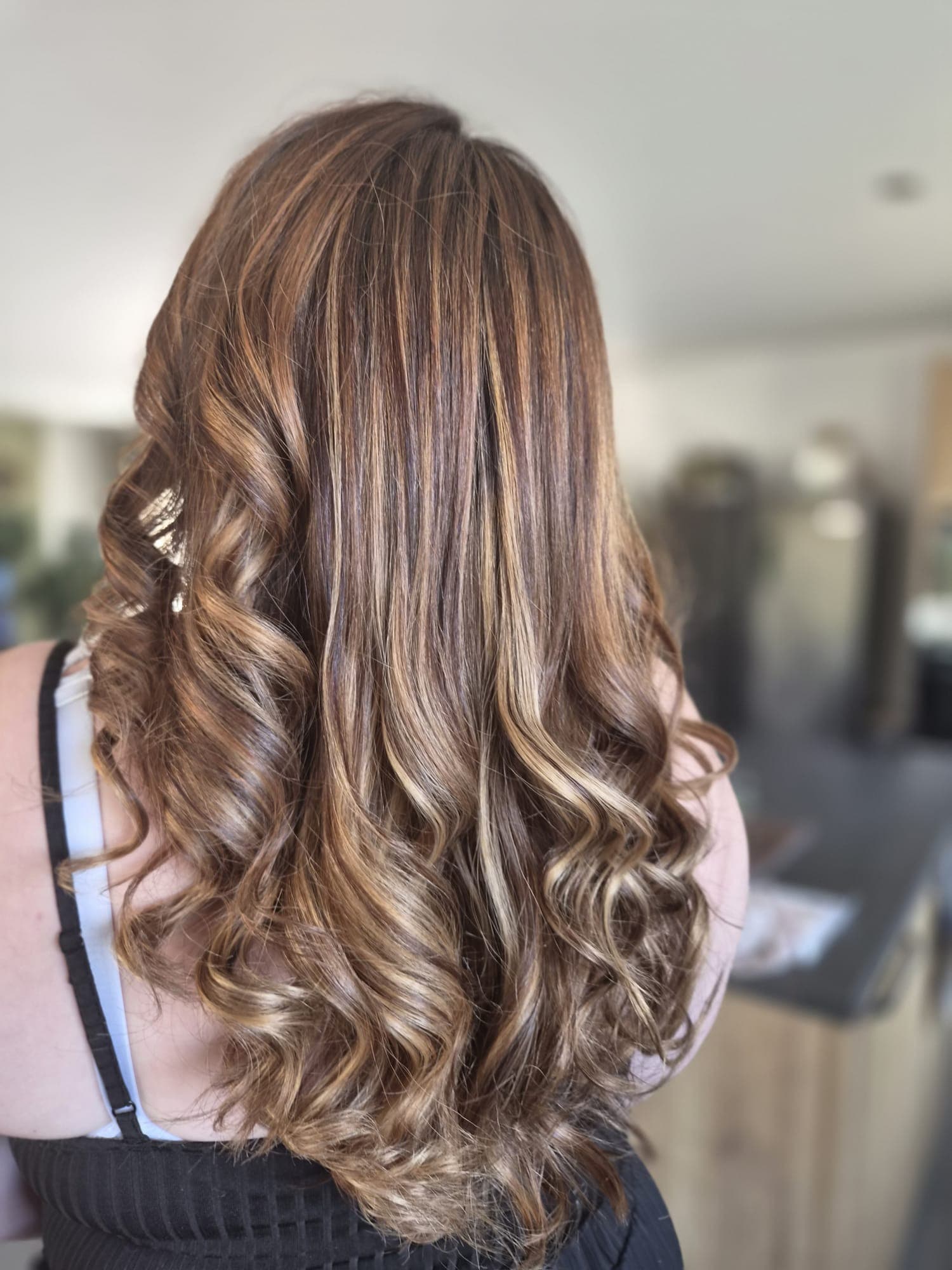 Balayage caramel sur longueurs bouclées, effet lumineux et naturel