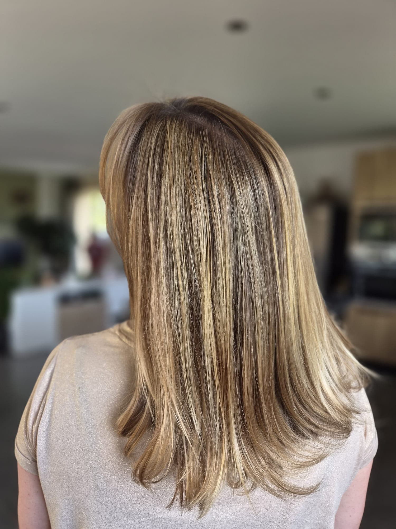 Balayage doré sur longueurs bouclées, résultat duo racines/pointes
