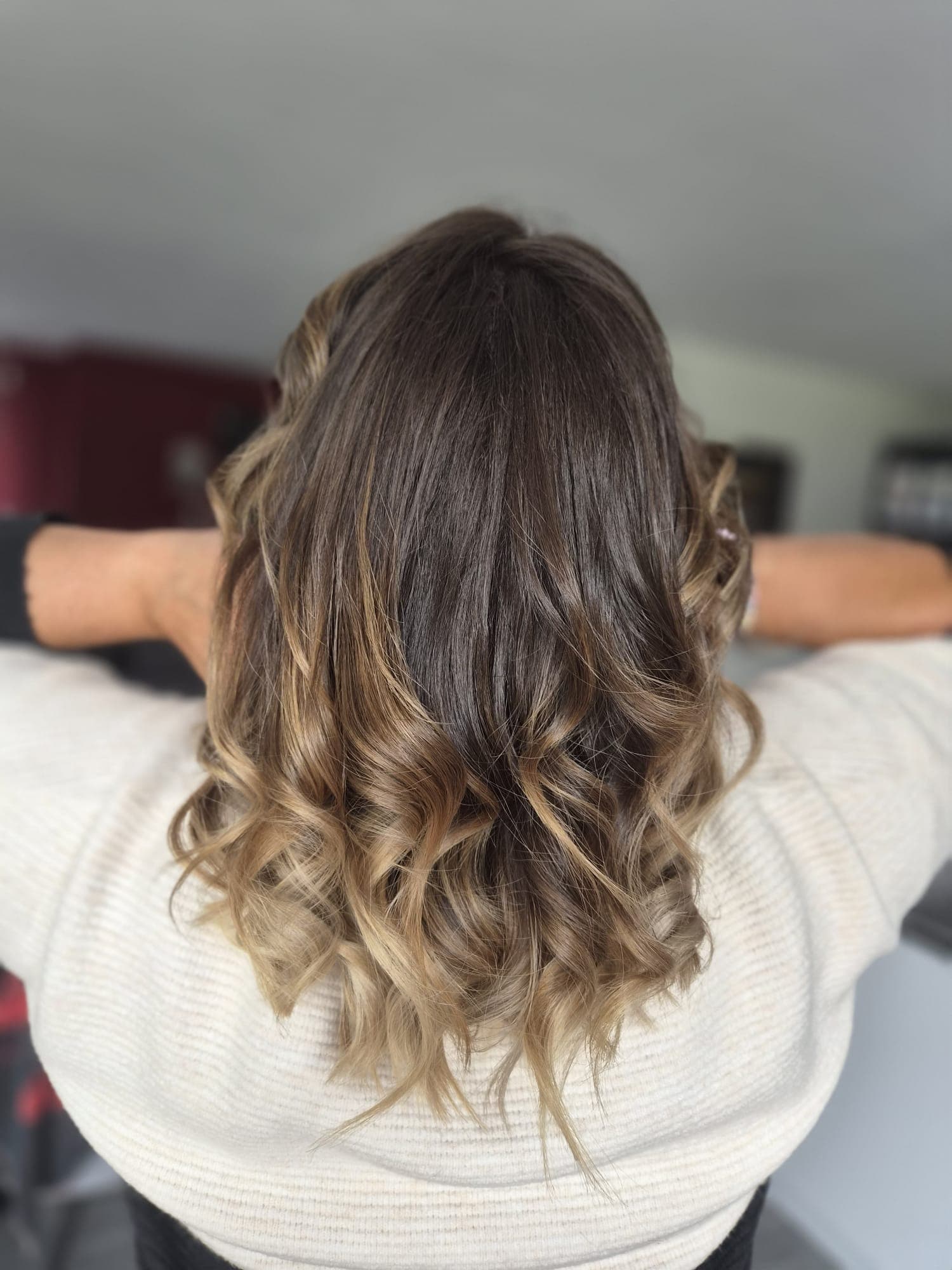 Ombré hair châtain vers blond miel, transition dégradée sur longueurs bouclées